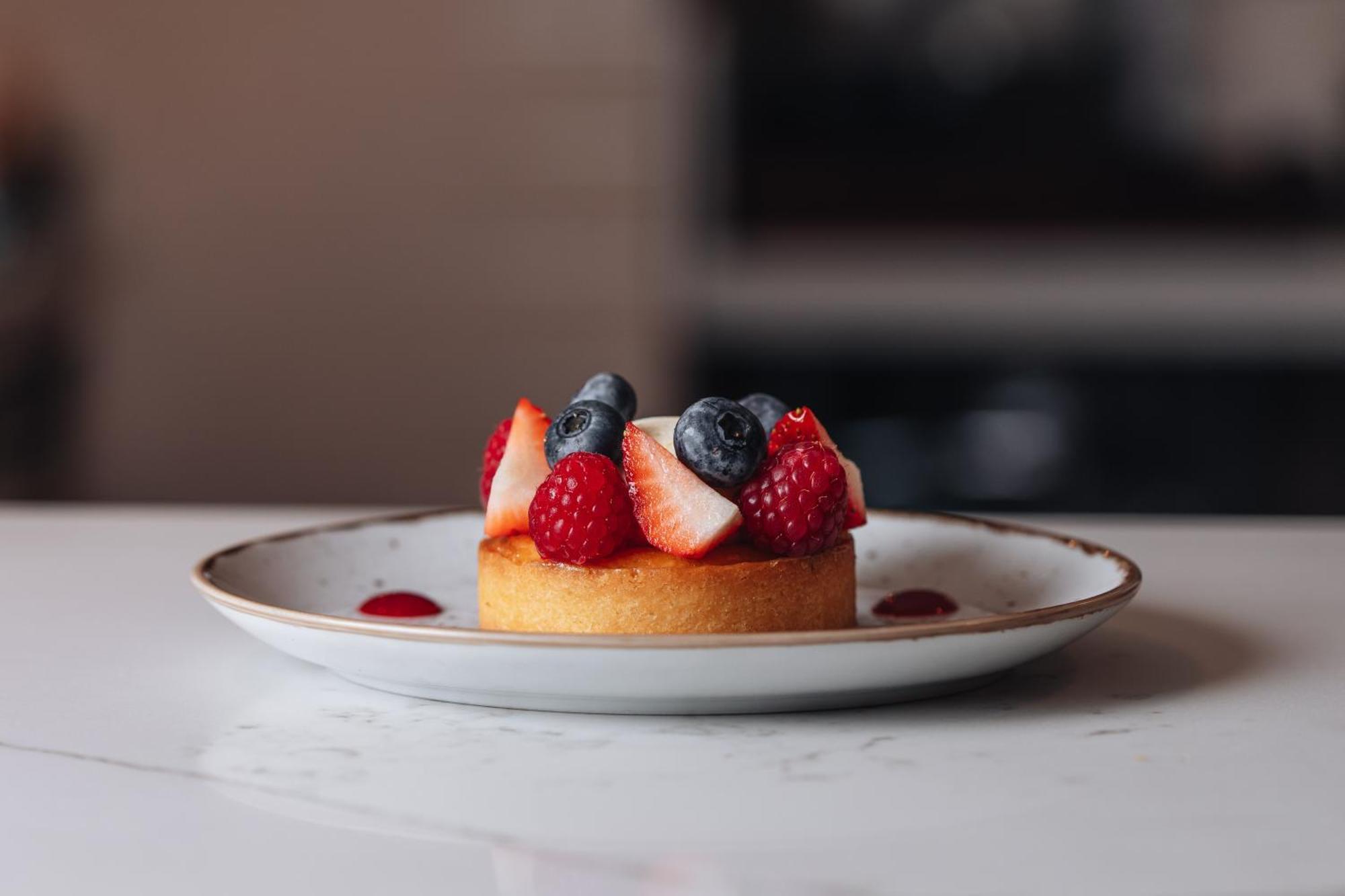 Middle Eight - Covent Garden - Preferred Hotels And Resorts London Exteriör bild The photo shows a delicious-looking dessert on a white plate. The dessert appears to be a small tart or cake topped with fresh strawberries, raspberries, and blueberries. It has a golden crust, and there are small dollops of a red sauce or fruit pure