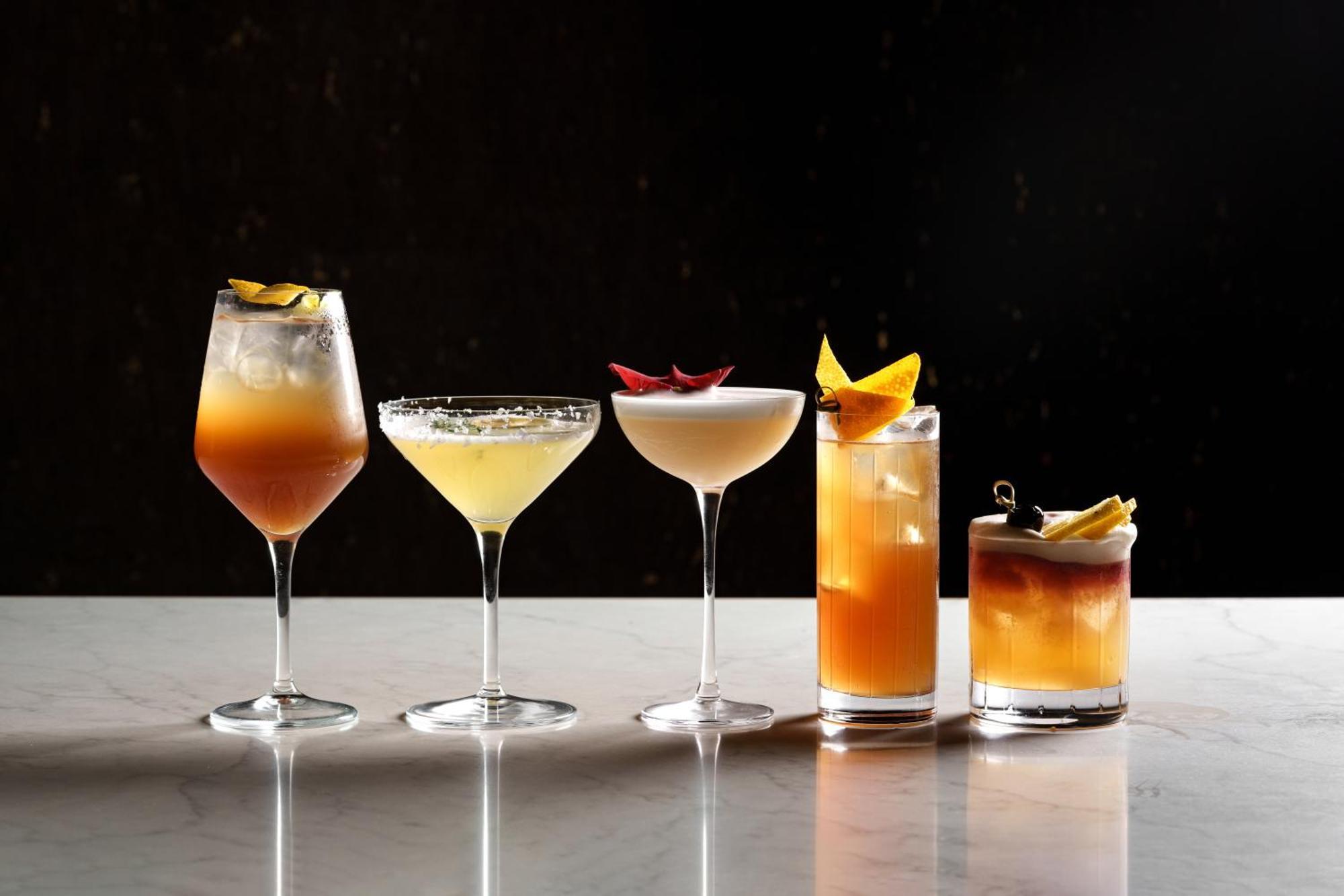 Middle Eight - Covent Garden - Preferred Hotels And Resorts London Exteriör bild The photo features a selection of five different cocktails lined up on a marble surface. Each drink is served in a distinct glass, showcasing a variety of colors and garnishes. 

1. The first cocktail is in a large wine glass, with a gradient color f
